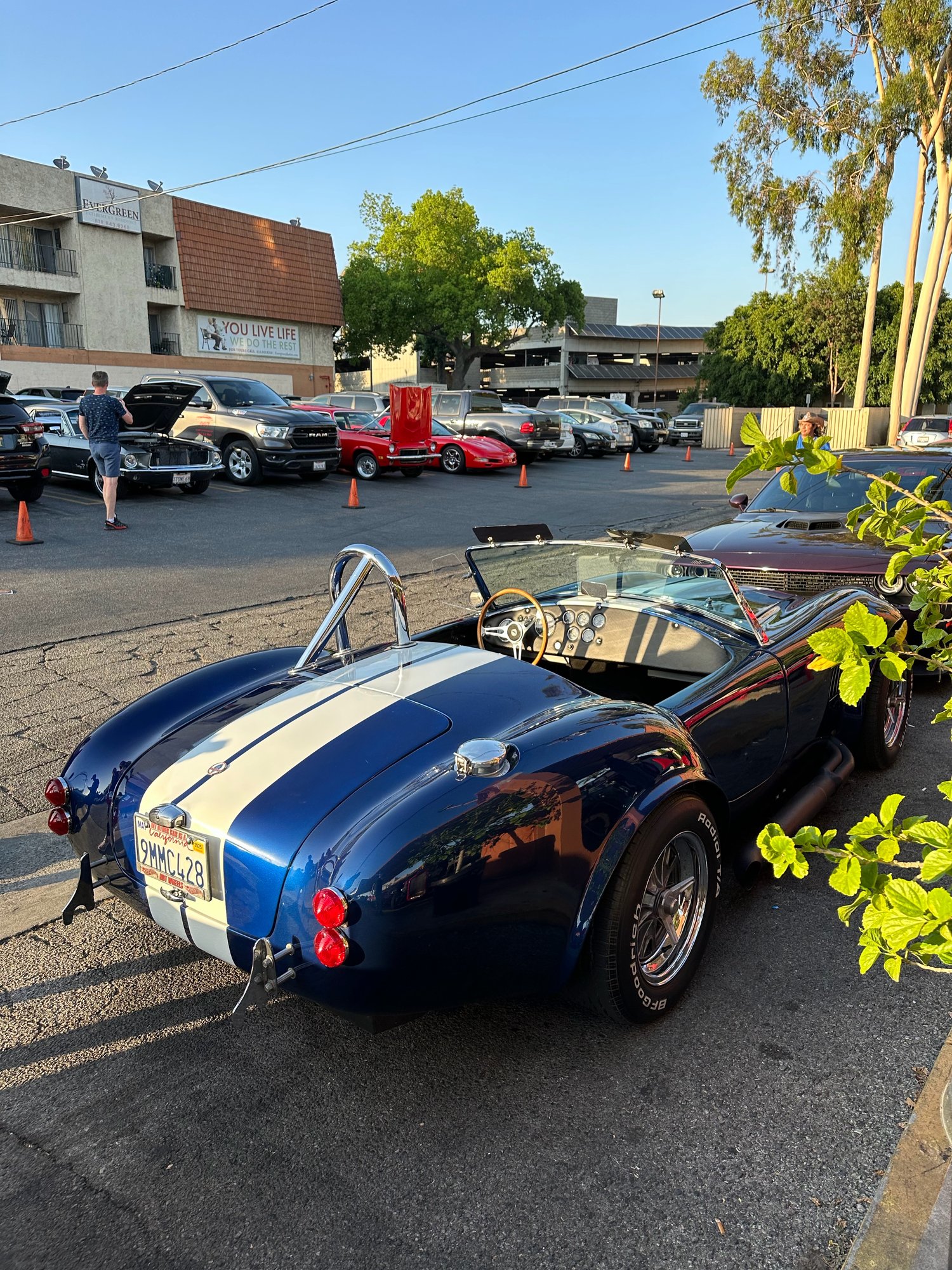 Blue Shelby Cobra replica with white stripes in the Bob's Big Boy Burbank parking lot, other cars with hoods up